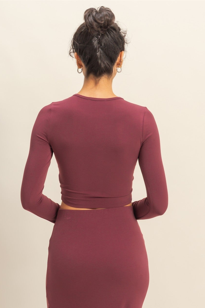 Maroon two-piece dress with a high slit on a beige background
